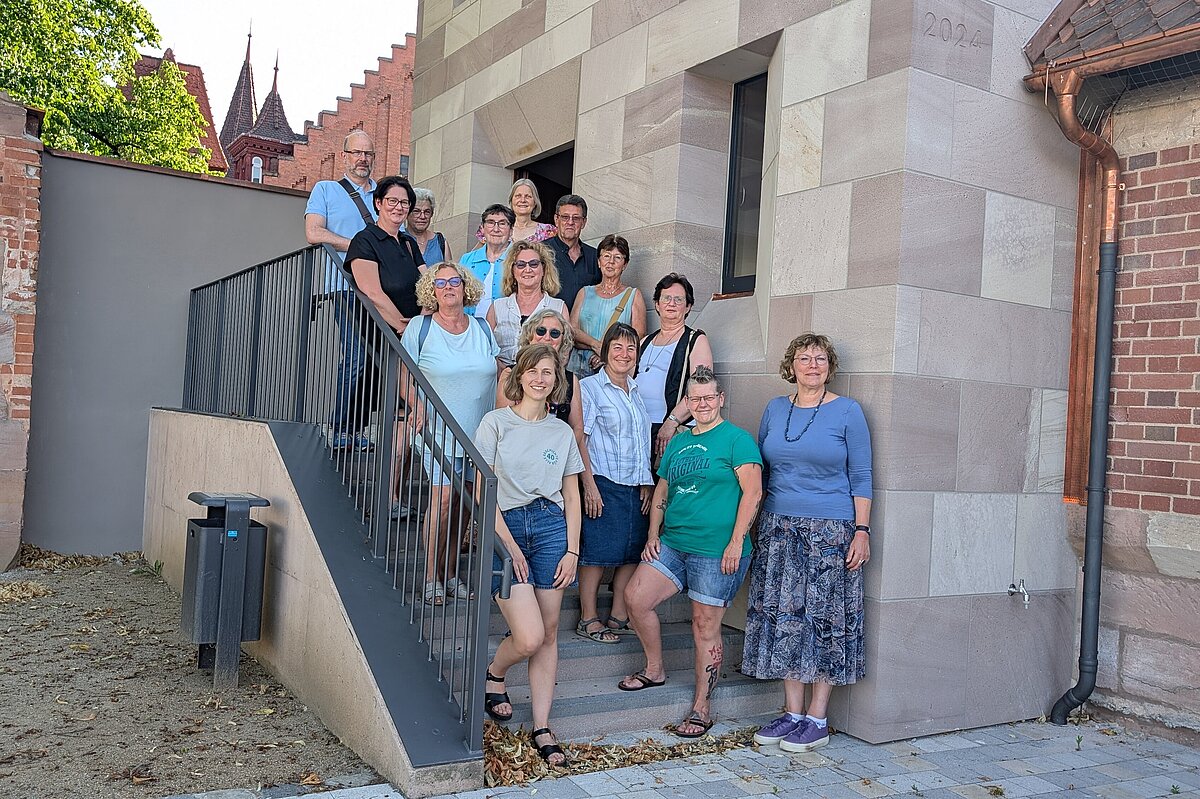 Ehrenamtliche Turmwächterinnen und Turmwächter auf der Treppe vor dem Turm "Blaues G". Gruppenbild der ca. 15 Ehrenamtlichen, die den Turm "Blaues G" künftig öffnen werden, auf der Treppe vor dem Turm.